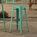 Two turquoise Lancaster Table & Seating outdoor barstools on a stone patio.