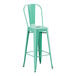 A mint green metal outdoor barstool with a backrest.