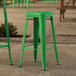 Two Lancaster Table & Seating jade green backless barstools on a stone patio.