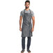 A man wearing a Mercer Culinary indigo denim bib apron with leather accents.