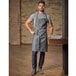 A man wearing a Mercer Culinary denim apron with leather accents.