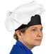 A woman wearing a white Uncommon Chef twill chef hat.