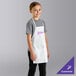 A young girl wearing a white Uncommon Chef child bib apron.