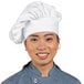 A woman wearing a white Uncommon Chef twill chef hat and smiling.