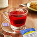 A glass cup of Bigelow Wild Blueberry with Acai tea with a tea bag on a saucer.