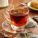 A glass cup of Steep Cafe By Bigelow English Breakfast Tea with a tea bag on a saucer.