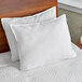 Two white Oxford Gold king size pillows on a bed with white bedding.