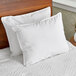 Two white Oxford Microgel king size pillows on a bed with white sheets.