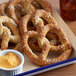 A tray of baked Dutch Country Foods gluten-free soft pretzels with mustard dipping sauce.