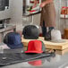 A navy blue Mercer Culinary trucker cap with a mesh back on a counter in a professional kitchen.