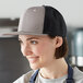 A woman wearing a Mercer Culinary gray trucker cap in a professional kitchen.