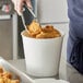 A person holding a Choice white food bucket filled with fried chicken.