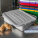 A gray Carlisle bus tub lid on a white plastic container filled with potatoes.