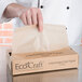 A person opening a Bagcraft Packaging EcoCraft dry wax deli paper bag.