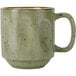 A green Tuxton China Yukon mug with brown specks and a handle.