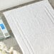 A white bath mat on a grey floor next to a digital scale.