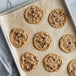 Preformed Rich's Jacqueline vegan chocolate chip cookie dough on a baking sheet with baked cookies.