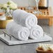 A stack of white Lavex Luxury hand towels on a tray.