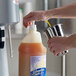 A person pouring J. Hungerford Smith banana syrup into a blender.