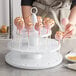 A woman using a Fox Run white cake pop stand with pink and gold star decorated cake pops.