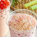 A close-up of a cup of pink bubble tea with pink rose boba.