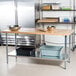 An Advance Tabco wood top work table with galvanized metal legs and an undershelf with two bowls on it.