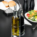 A Tablecraft chrome rack holding a bottle of olive oil and a bottle of vinegar.