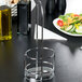 A Tablecraft Gemelli chrome metal cruet rack on a table with salad and oil.