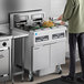 A man standing next to a Frymaster electric floor fryer with open frypots.