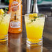 Two glasses of yellow liquid with a mango on top.