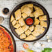 A Tablecraft brown melamine platter with a variety of pizza slices and a bowl of red sauce on a table.