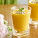 A glass of yellow mango pudding with whipped cream and mint leaves.