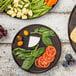 A Tablecraft brown round melamine platter with vegetables and bread.