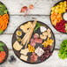 A Tablecraft brown melamine platter with a variety of food on a table.
