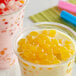 Two cups of bubble tea with yellow mango boba.