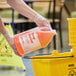 A hand in a glove pouring Advantage Chemicals orange degreaser into a yellow container.