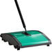 A green and black Bissell Commercial floor sweeper with a handle.