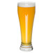 A close up of a Libbey Giant Pilsner Glass full of beer with foam.