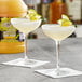 Two glasses of Finest Call lime sour mix with lime wedges on the rim on a table in a cocktail bar.