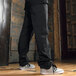 A person wearing Uncommon Chef pinstripe pants and sneakers.