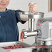 A woman using the Avantco meat grinder attachment to grind meat.