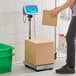 A person weighing a box on an AvaWeigh digital receiving scale.