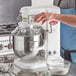 A person pouring liquid into a white Avantco countertop mixer.