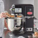 A person using an Avantco black countertop mixer to mix eggs in a bowl.