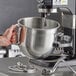 A person holding an Avantco 8 qt. metal mixer bowl.