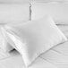 A white Oxford King Size waterproof pillow protector on a white pillow on a bed.