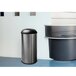 An Ex-Cell Kaiser stainless steel trash can with a black lid.