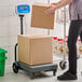 A person weighing a white box on an AvaWeigh digital receiving scale.