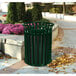 A green Ex-Cell Kaiser Streetscape outdoor trash can on a sidewalk.