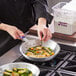 A person cooking food in a Choice aluminum fry pan with a purple allergen-free silicone handle.